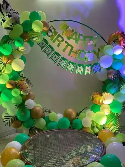 A jungle-themed birthday party with a circular balloon arch. This setup includes a "Happy Birthday" banner and animal-shaped foil balloons.