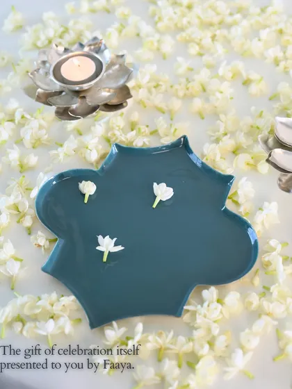 The gift of celebration itself. This image features our Aakar tray in a tranquil teal, adorned with a few simple mogra flowers. It highlights the elegant curves and serene beauty of the design.