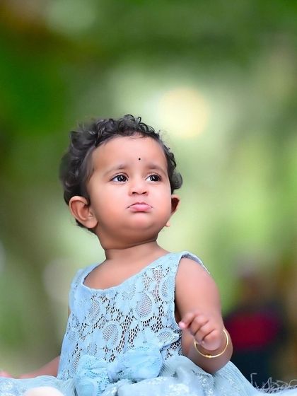 A beautiful outdoor portrait of a baby girl with a soft, blurry green background that makes her stand out.