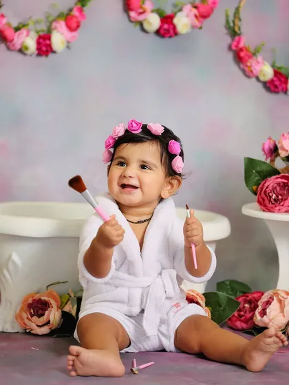 A little makeup artist at work. This floral spa-themed sitter session is a fun and girly concept, complete with a mini bathrobe and makeup brushes.