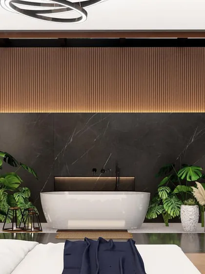 A view from the bed looking into the integrated bathroom area. The freestanding tub is the centerpiece, set against a black marble wall and accented with warm wood paneling and indoor plants.