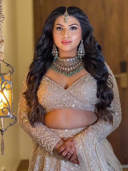 A direct portrait of the bride, showcasing her stunning reception look. The makeup is designed to sparkle and shine under the lights.