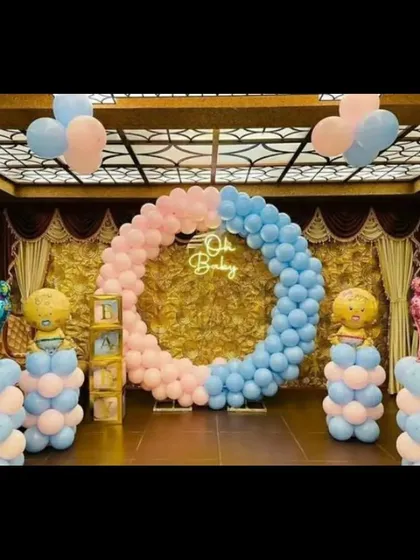 An elegant "Oh Baby" themed baby shower decoration. The circular balloon arch uses pink and blue pastel balloons, with a neon sign in the center. This setup is perfect for a party in a banquet hall or a large living room.