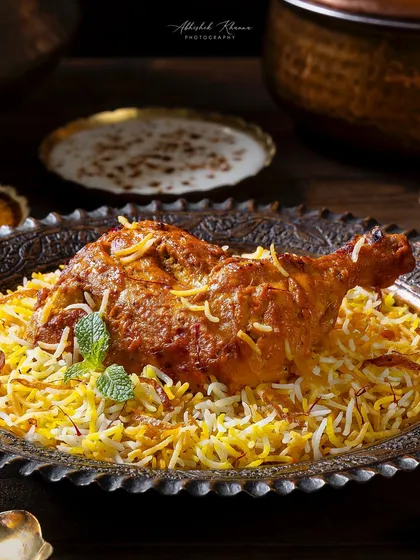 Zafrani Chicken Dum Biryani, focusing on the chicken leg piece over a bed of fragrant rice. This close-up shot for The Nawaab's is designed to be visually impactful.