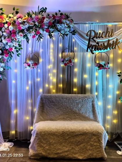 We can personalize your engagement decor with custom name signs, as seen here. This setup includes a floral arch, hanging floral hoops, and a backdrop of warm fairy lights.