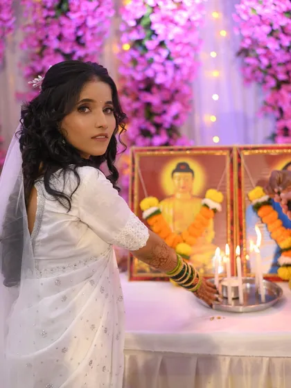 The bride is lighting candles as part of her Buddhist wedding ceremony. Her hairstyle is elegant and keeps her hair neatly away from her face.