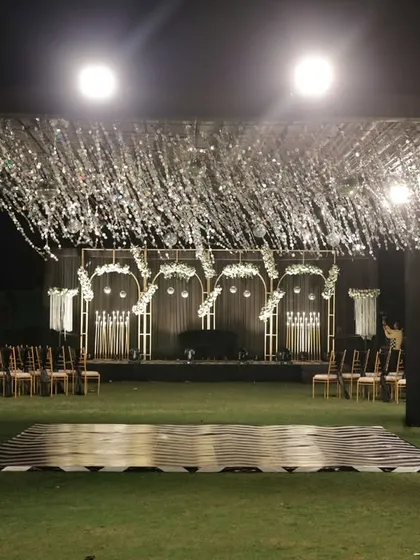The Sangeet stage viewed from a distance, highlighting the impressive lighting and tassel canopy.