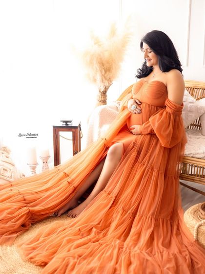 The full, beautiful train of this orange gown is on display in this elegant seated portrait.