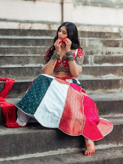 A pensive moment on ancient stone steps. The vibrant, patchwork lehenga stands out beautifully against the muted tones of the historic location.