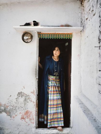 A portrait for House of Wandering Silk, taken in a rustic doorway. The setting complements the brand's focus on handmade, authentic textiles.