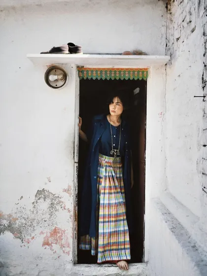 A portrait for House of Wandering Silk, taken in a rustic doorway. The setting complements the brand's focus on handmade, authentic textiles.