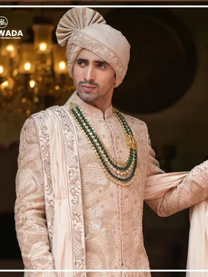 A close-up of the groom, focusing on the fine craftsmanship of the sherwani and the complementary accessories, including the ornate ring and the layered necklace.