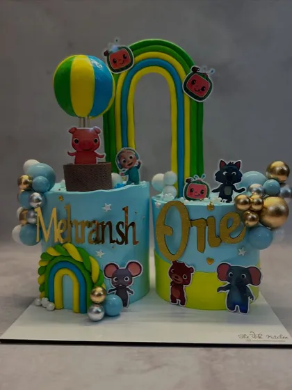 I created this Cocomelon twin cake set for Mehransh's first birthday. It features two separate cakes decorated with characters and elements from the popular show, like rainbows and a hot air balloon, making it perfect for larger celebrations.