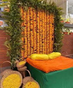 For a pure, traditional Haldi ceremony, we created this backdrop using a dense wall of orange marigold garlands framed with fresh green leaves. We also provide baskets of loose flower petals for the rituals.