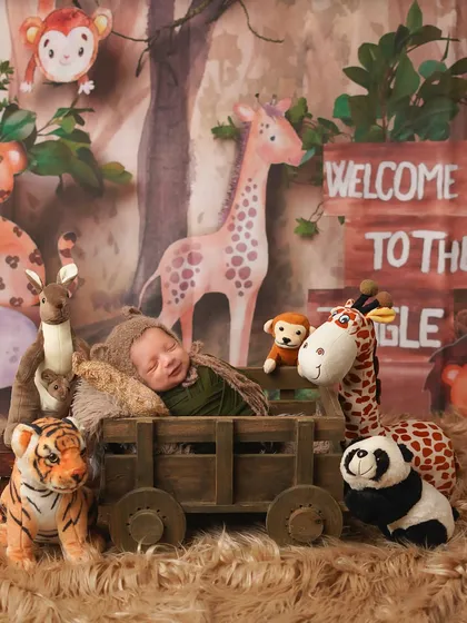 Welcome to the jungle! The full safari setup, with the newborn surrounded by friendly plush animals like a giraffe, tiger, and panda.