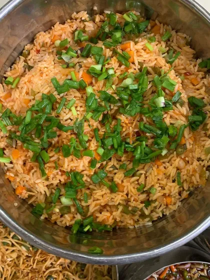 A large serving of flavorful Schezwan Fried Rice, garnished with spring onions.