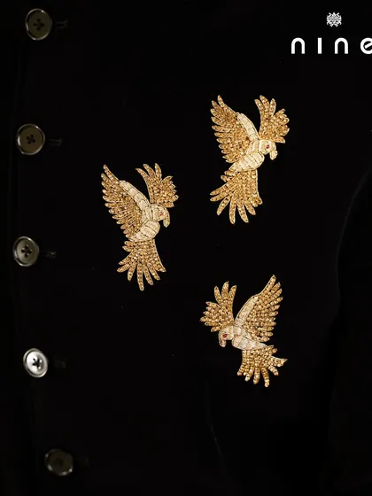 A detailed close-up of the antique gold embroidered flying birds. The level of detail in the threadwork gives these motifs a lifelike, three-dimensional quality.