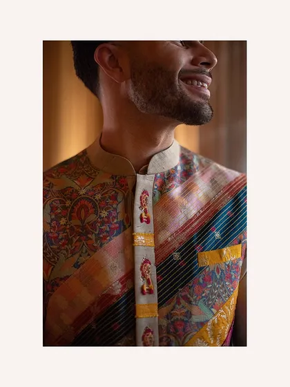A close-up on the intricate details of the groom's jacket. The small, embroidered figures add a touch of whimsy and character to the classic ensemble.