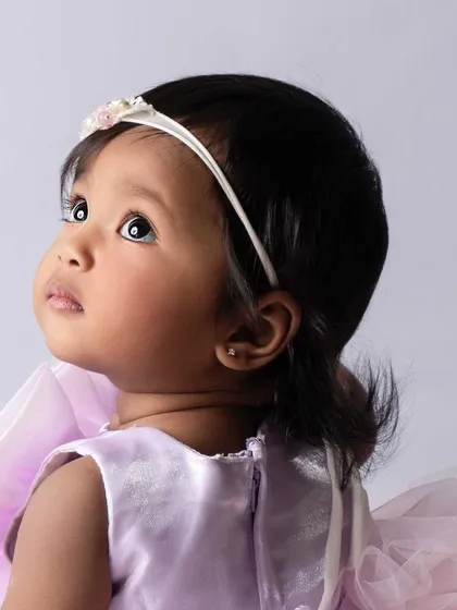A quiet, contemplative moment during her first birthday session. Her wide, curious eyes look up, creating a sweet and soulful portrait.