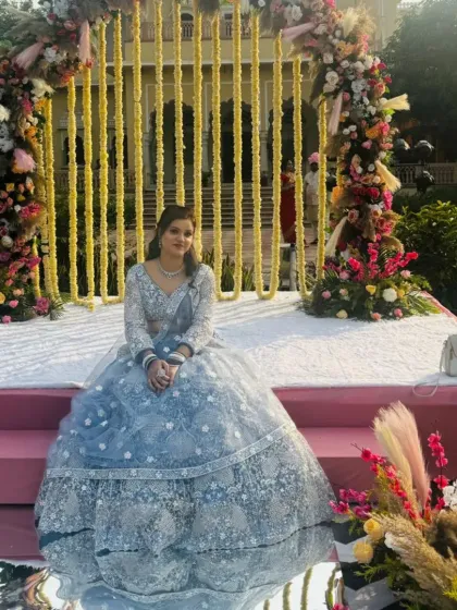The same powder blue lehenga, pictured at a beautiful daytime wedding venue. The color and style are perfect for an outdoor event.