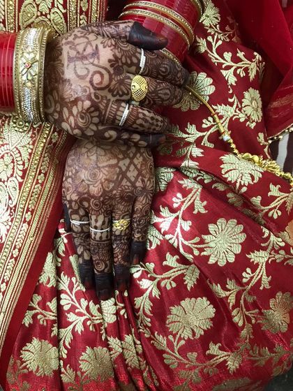 The back of the hands, showing the rich color against the bride's red and gold saree.