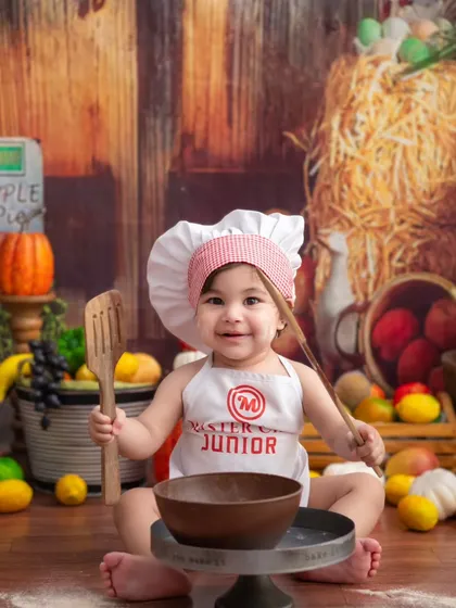 Ready to cook! This little chef, armed with a wooden spoon, is ready to whip up something delicious in her rustic kitchen.