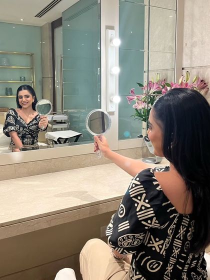 The final reveal. Our client admires her reflection after a session with us, showcasing a natural yet polished makeup look that gives her confidence and radiance.