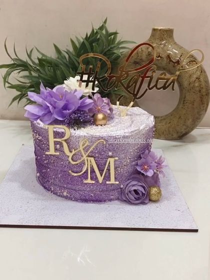 Our purple beauty. This bestselling single-tier design is perfect for a Roka ceremony, covered in purple glitter with a custom hashtag and initial toppers.