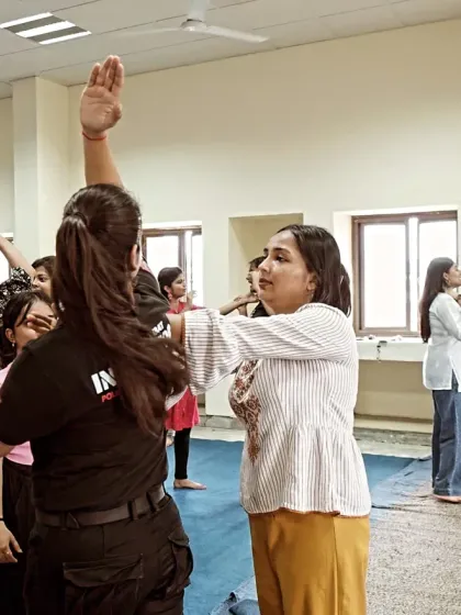 A female instructor guides participants through a blocking drill during a corporate workshop for women.