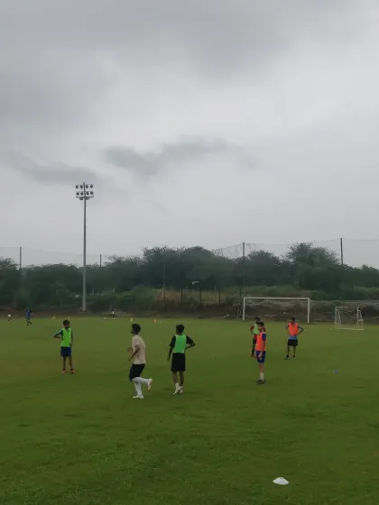 A view of the training ground with players spread out, engaged in various activities.