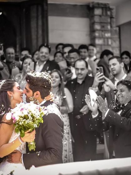 A classic "just married" moment, as the couple kisses while being showered with confetti by their guests.