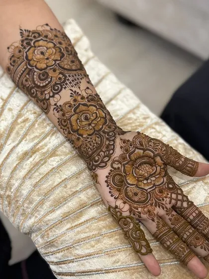 This is a classic Arabic floral henna design, perfect for festive occasions. The pattern flows from the forearm down to the fingers, featuring large, shaded roses and leafy vines with plenty of open skin for a bold contrast.