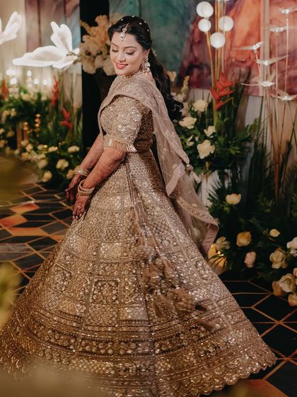 A beautiful twirling shot of the bride at her engagement, her golden lehenga shining under the lights.