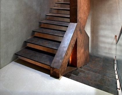 A detail of the staircase base, where the metal structure meets the floor. The design is precise and sculptural, showcasing the craftsmanship and attention to detail that goes into every element.