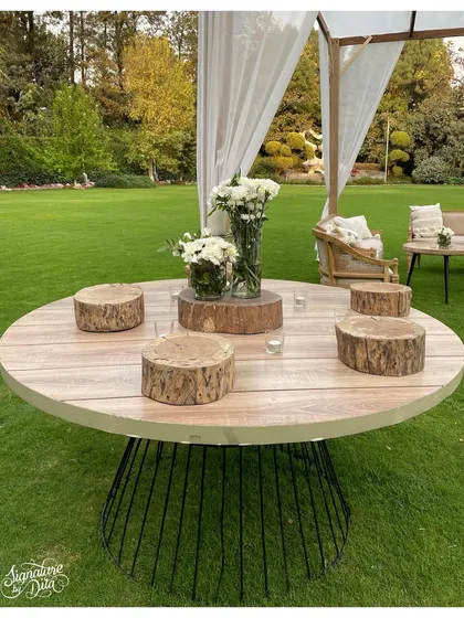 A simple yet striking centerpiece using rustic wood slices as platforms for minimalist white floral arrangements. This design brings a touch of nature to the tabletop.