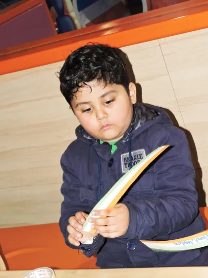 A young boy is focused on making a tricolor paper craft during our Independence Day workshop.