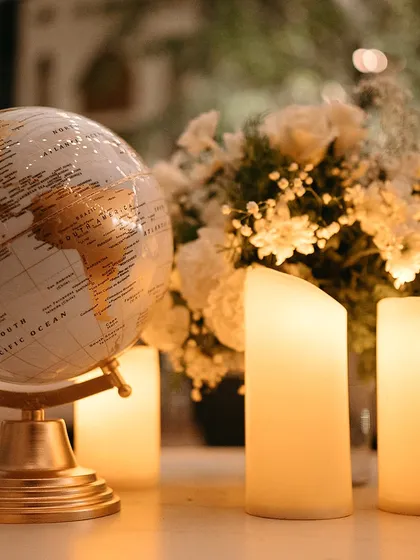 A globe centerpiece surrounded by candles and white flowers, creating a romantic and worldly tablescape.