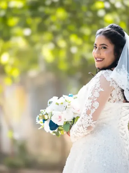 A bright and happy bridal portrait. The bride's joyful smile and the beautiful sunny backdrop make this a perfect wedding day photo.
