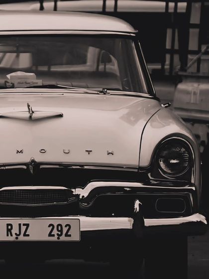 A close up of a vintage Plymouth car, captured in a nostalgic sepia tone. This photograph evokes a sense of timelessness and the classic charm that can be found in the corners of Rajasthan.