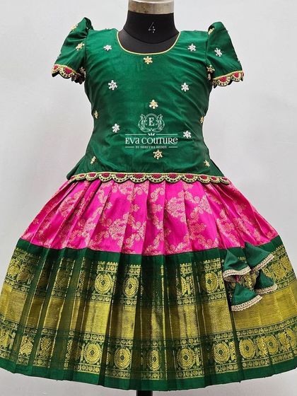 A timeless combination of bottle green and pink in pure Kanchi Pattu. The blouse is sprinkled with delicate floral butties, and the skirt has a traditional gold and green border.