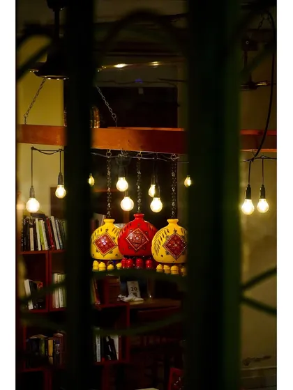 A peek through the green staircase railings reveals the warm glow of our unique lamps and the book-filled shelves of our library.