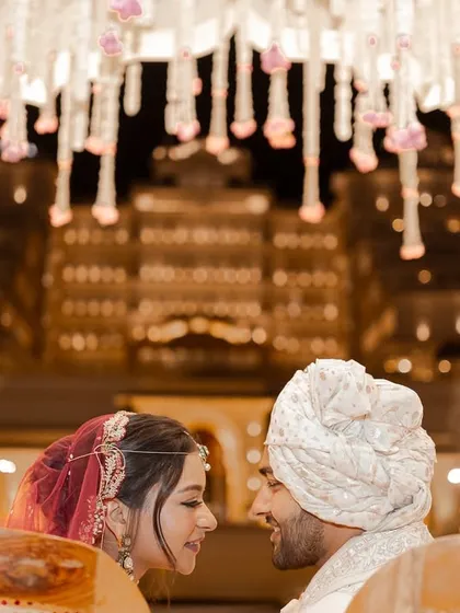 Under a beautifully decorated mandap with a grand palace illuminated in the background, the couple shares an intimate glance. This frame captures the romance and scale of a destination wedding in Jaipur.
