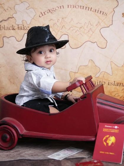 Adventure awaits! A creative travel-themed shoot with a baby boy in a toy car, complete with a passport and a world map background.