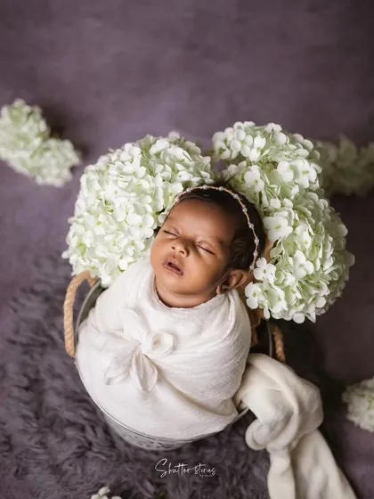 A beautiful portrait featuring a baby in a white wrap, surrounded by white hydrangeas for a clean and angelic look.