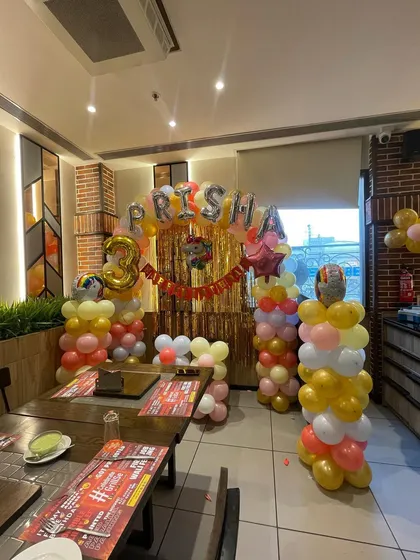 Another view of the colorful birthday decoration, showing how the different elements like the balloon pillars and backdrop come together to create a festive corner in the restaurant.