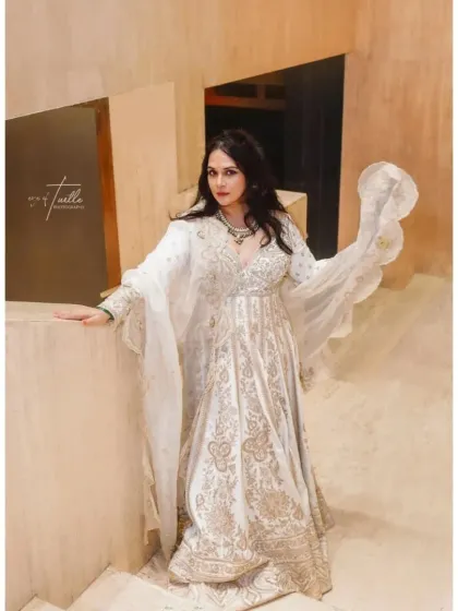 A stunning portrait of the bride in her elegant white and gold Anarkali, ready for one of her pre-wedding events. Her pose is full of grace and confidence.