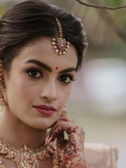 A close up portrait highlighting the bride's serene expression and her stunning jewelry. The custom blouse and maang tikka are perfectly coordinated for her special day.