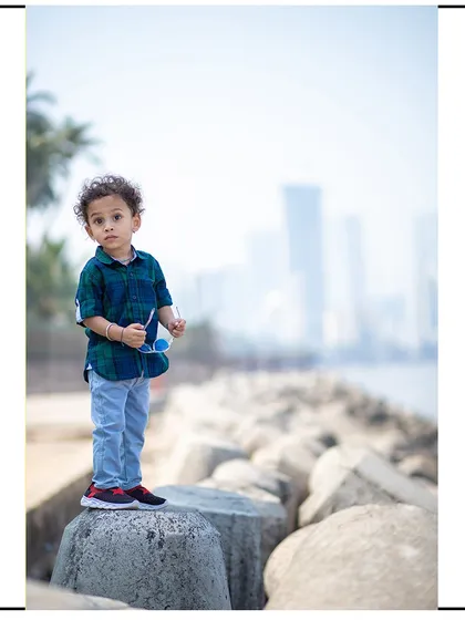 A striking portrait with the child in the foreground and the blurred Mumbai skyline behind him, creating a beautiful sense of depth.