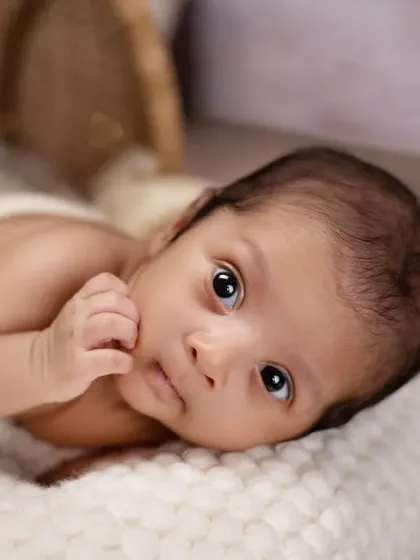 A quiet moment of contemplation for this little one. This close-up portrait on a soft white blanket captures the beautiful, soulful eyes of a newborn.