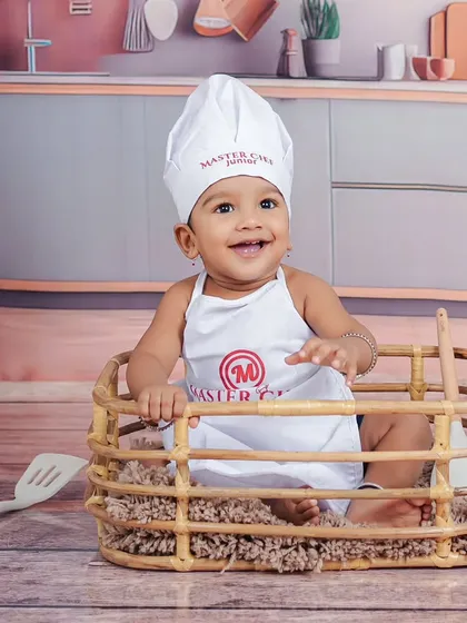 A close-up portrait of the little chef, showing off his personalized apron and hat.